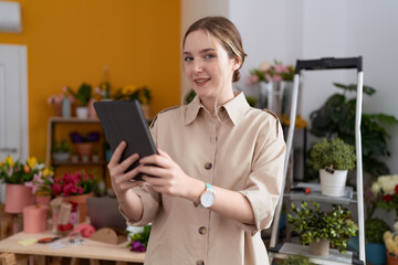 Poster - Young caucasian woman florist smiling confident using touchpad at flower shop