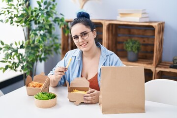 Poster - Young caucasian woman eating take away food sitting on table at home