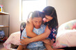 © Caia Image - Affectionate mother hugging and comforting daughter in bedroom