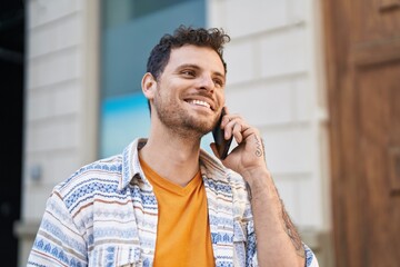 Wall Mural - Young hispanic man smiling confident talking on the smartphone at street