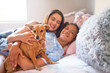 © Caia Image - Portrait happy mother, disabled daughter and dog cuddling on bed