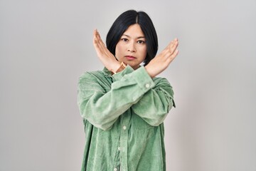 Wall Mural - Young asian woman standing over white background rejection expression crossing arms doing negative sign, angry face