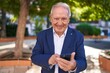 © Krakenimages.com - Middle age grey-haired man smiling confident using smartphone at park