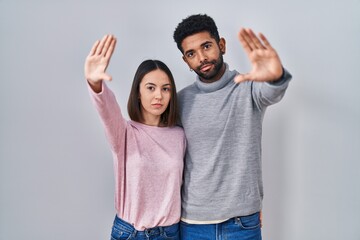 Sticker - Young hispanic couple standing together doing frame using hands palms and fingers, camera perspective