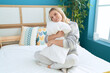 © Krakenimages.com - Young blonde woman hugging pillow sitting on bed at bedroom