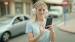 © Krakenimages.com - Young blonde woman listening to music standing at street