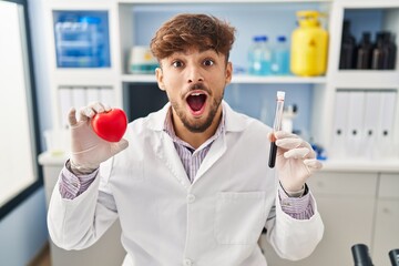 Sticker - Arab man with beard working at scientist laboratory holding blood samples celebrating crazy and amazed for success with open eyes screaming excited.