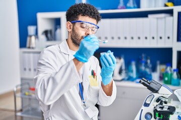 Sticker - Young arab man wearing scientist uniform holding pills at laboratory