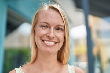 Wall Mural - Young blonde woman smiling confident standing at street