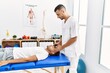 © Krakenimages.com - Two hispanic men physiotherapist and patient having rehab session massaging head at clinic