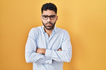 Canvas Print - Hispanic man with beard standing over yellow background skeptic and nervous, disapproving expression on face with crossed arms. negative person.