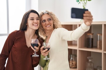 Canvas Print - Two women mother and daughter drinking wine make selfie by smartphone at home