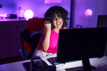 Poster - Young middle eastern woman streamer playing video game with winner expression at gaming room