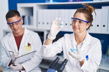 Sticker - Man and woman scientists write on document holding pills at laboratory