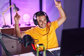 Poster - Young hispanic man streamer playing video game dancing at gaming room