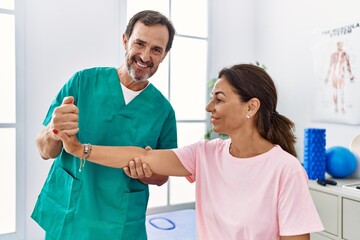 Canvas Print - Middle age man and woman smiling confident stretching arm having rehab session at physiotherapy clinic