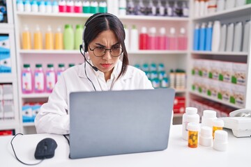 Poster - Young arab woman working at pharmacy drugstore using laptop skeptic and nervous, frowning upset because of problem. negative person.