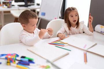 Wall Mural - Adorable girl and boy drawing on notebook sitting on table at kindergarten