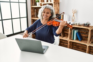 Canvas Print - Middle age grey-haired woman playing online violin concert at radio studio.