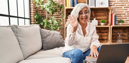 Canvas Print - Middle age woman having video call sitting on sofa at home