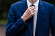 Elegant man tying his tie over black shirt. Adjusting tie. Black and violet. Young business man dressing, isolated on black background. Groom adjusting his tie.