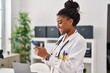 © Krakenimages.com - African american woman wearing doctor uniform using smartphone working at clinic