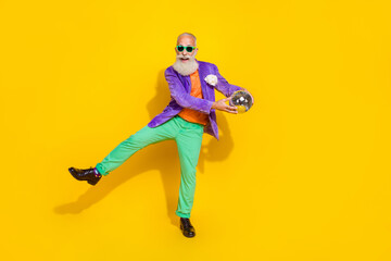 Sticker - Full length photo of funny cheerful man wear purple velvet jacket dancing holding discotheque ball walking isolated yellow color background