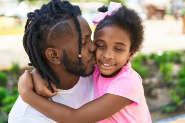 Father and daughter smiling confident hugging each other and kissing at park