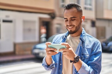 Wall Mural - Young hispanic man smiling confident watching video on smartphone at street