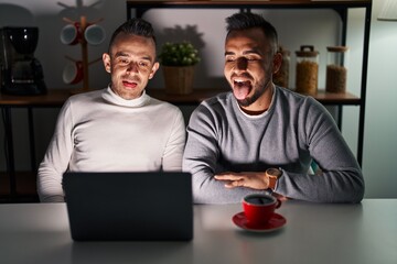 Canvas Print - Homosexual couple using computer laptop sticking tongue out happy with funny expression. emotion concept.