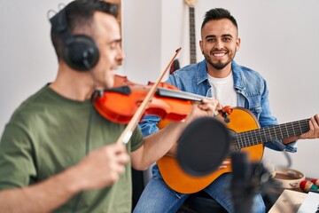 Two men musicians playing classical guitar and violin at music studio