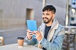 © Krakenimages.com - Young hispanic man having video call sitting on table at coffee shop terrace