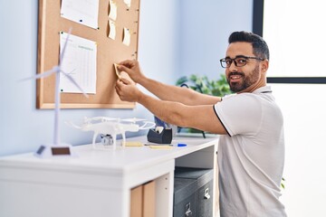 Sticker - Young hispanic man business worker hanging reminder paper on cork board at office