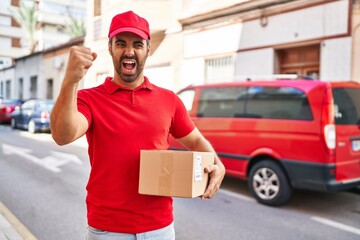 Sticker - Young hispanic man with beard wearing delivery uniform and cap holding box annoyed and frustrated shouting with anger, yelling crazy with anger and hand raised