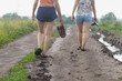 © Dmitry Strizhakov - Two young girls walk along a muddy dirt road after the rain.