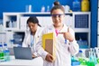 © Krakenimages.com - Mother and young daughter working at scientist laboratory smiling happy pointing with hand and finger