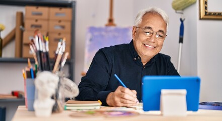 Canvas Print - Senior man having online draw lesson sitting on table at art studio