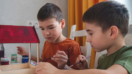 kids two boys decorate a wooden birdhouse