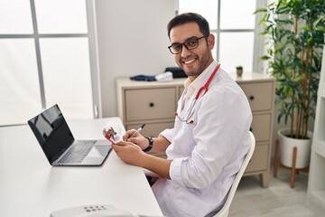 Poster - Young hispanic man wearing doctor uniform working at clinic