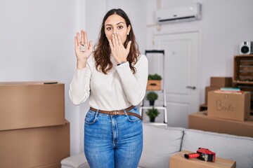 Canvas Print - Young hispanic woman holding keys of new home covering mouth with hand, shocked and afraid for mistake. surprised expression