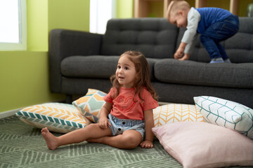 Sticker - Adorable girl and boy sitting on floor with relaxed expression at home