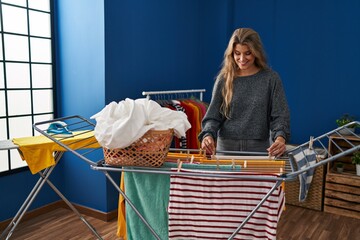 Wall Mural - Young blonde woman smiling confident hanging clothes on clothesline at laundry room
