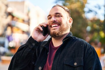 Wall Mural - Young hispanic man smiling confident talking on the smartphone at park