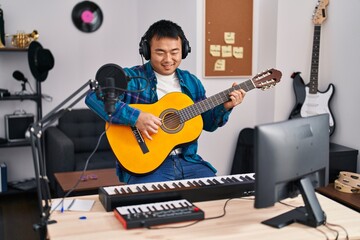 Poster - Young chinese man guitarist playing classical guitar at music studio