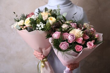 Wall Mural - Woman with bouquets of beautiful flowers on beige background, closeup