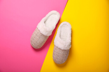 Pair of beautiful soft slippers on colorful background, top view
