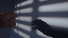 Dramatic Hand Move Touching And Moving Over A Wall With Window Blind Shadows. Male Hand Going Over Dark Wall Scene With Dramatic Shadows Casting Hard. Jail Or Freedom Context. Fingers Touching Wall