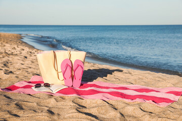 Wall Mural - Towel with book and beach accessories on sand near sea, space for text