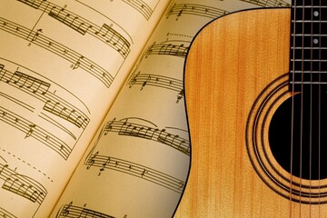 Wall Mural - The fretboard of an old vintage acoustic guitar with strings next to sheets of music. A musical instrument.