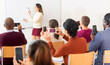 © JackF - .Female teacher standing in front of whiteboard and people shooting on smartphones her